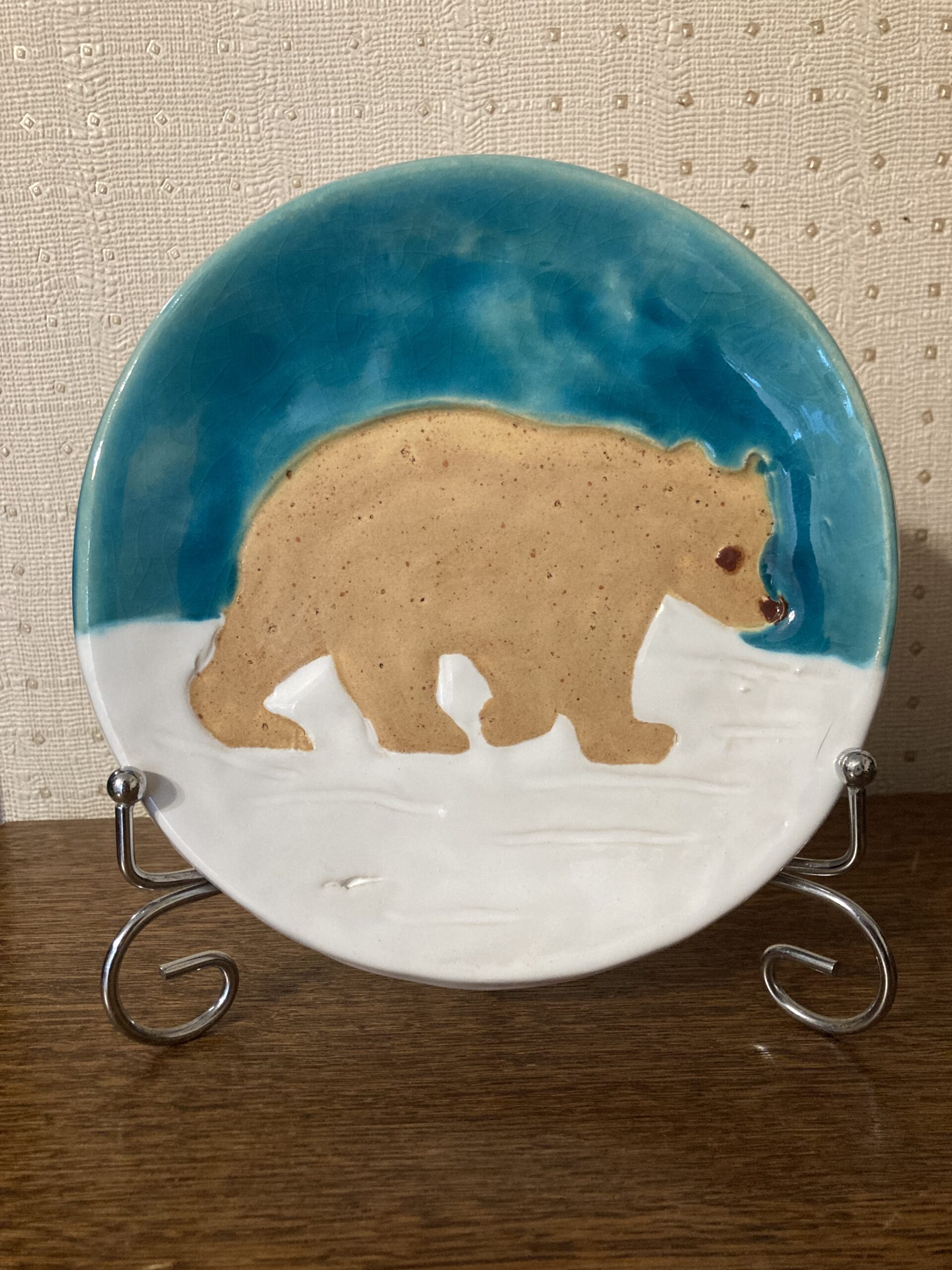 тарелка диаметр – 16 см, используется пищевая глазурь, можно использовать, как тарелка для еды. на тарелке изображен бежевый мишка у него коричневый глаз и нос. он направляется по своим делам по белоснежному льду. над медведем чистое, голубое небо. тарелка продается вместе с подставкой